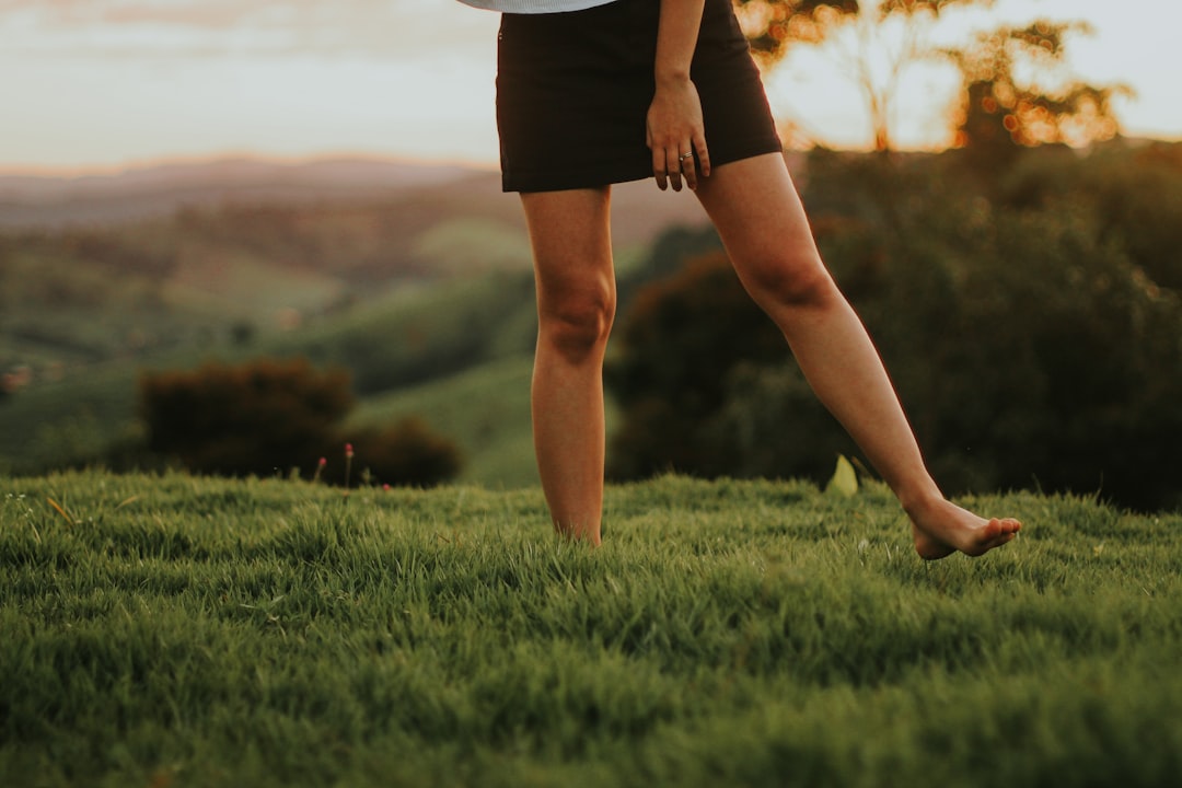 woman in black shorts standing on green grass field during daytime