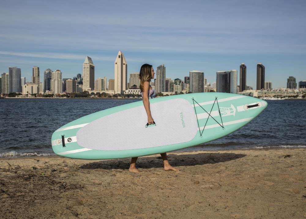 woman in black bikini holding white surfboard on beach during daytime