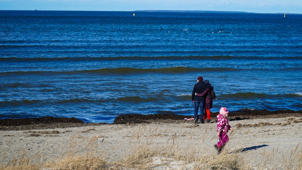 hombre y mujer caminando por la orilla del mar durante el día