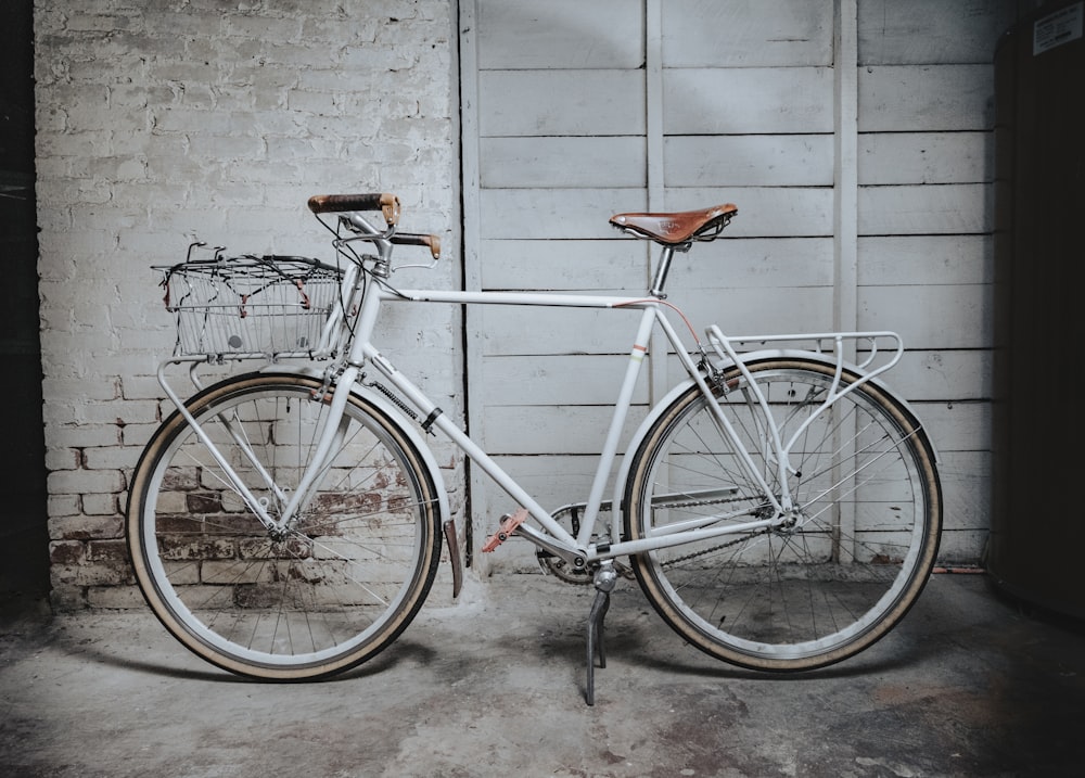 white and brown road bike leaning on gray concrete wall