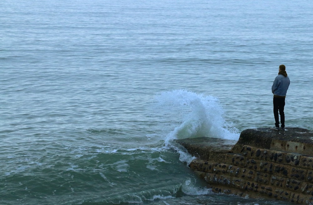 formação rochosa marrom no mar durante o dia