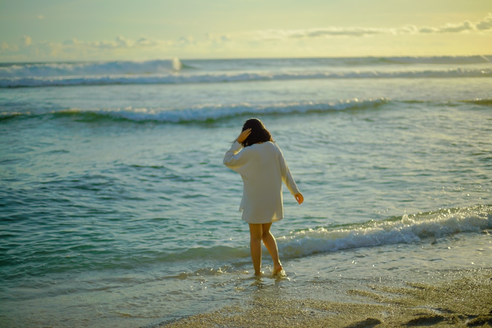 woman in white dress standing on beach during daytime