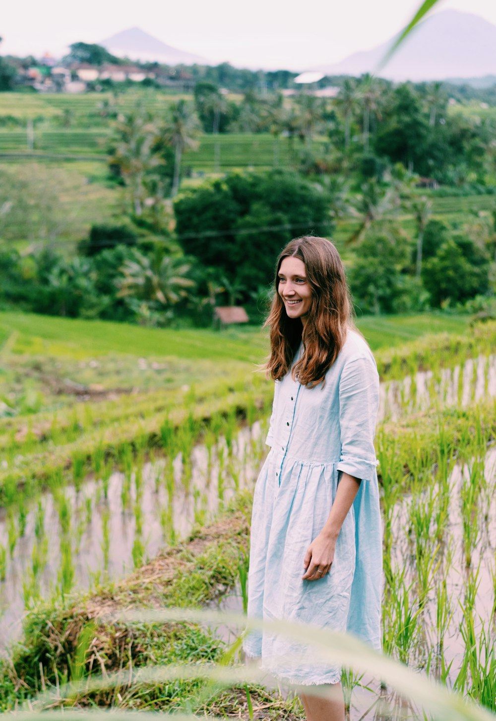 donna in camicia bianca a maniche lunghe in piedi sul campo di erba verde durante il giorno