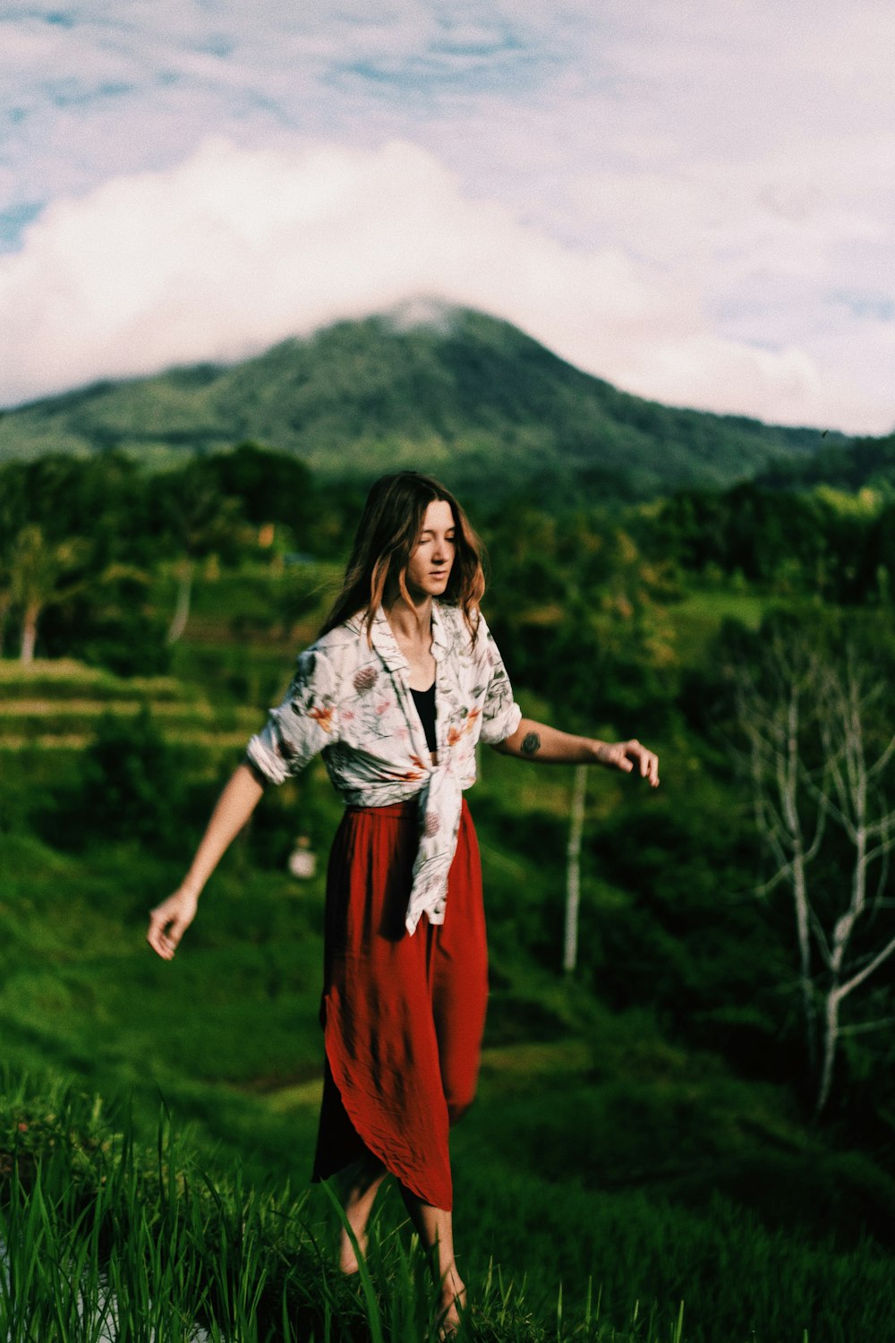 woman in white and red dress standing on green grass field during daytime