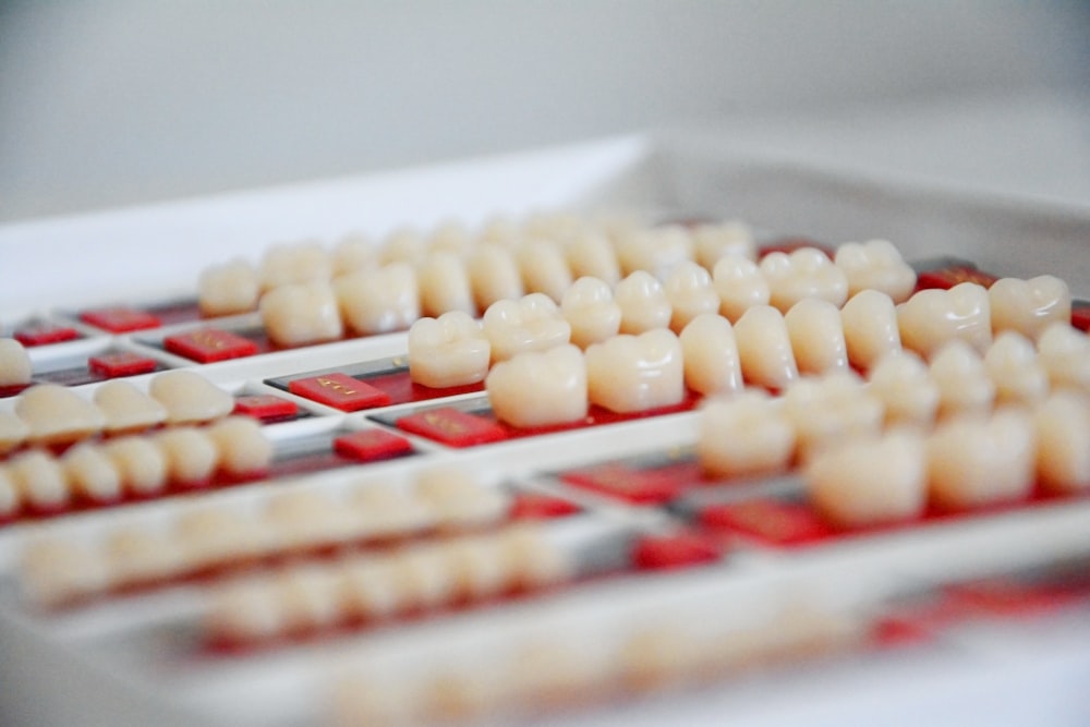 white dental veneers on a red and white tray. The veneers are professional-grade and not homemade,