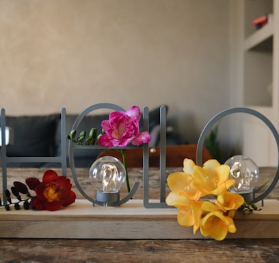 yellow and purple moth orchids in clear glass vase on brown wooden table