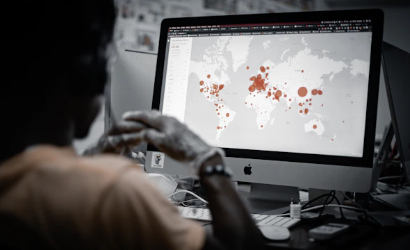 Close-up of a cybersecurity expert analyzing digital threat maps on multiple screens