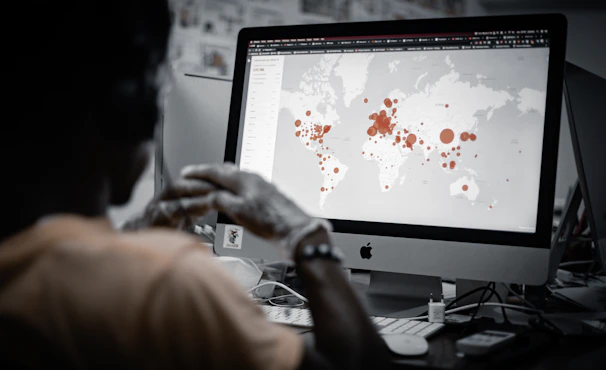 A team analyzing real-time data visualizations on laptops in a field office surrounded by community maps.