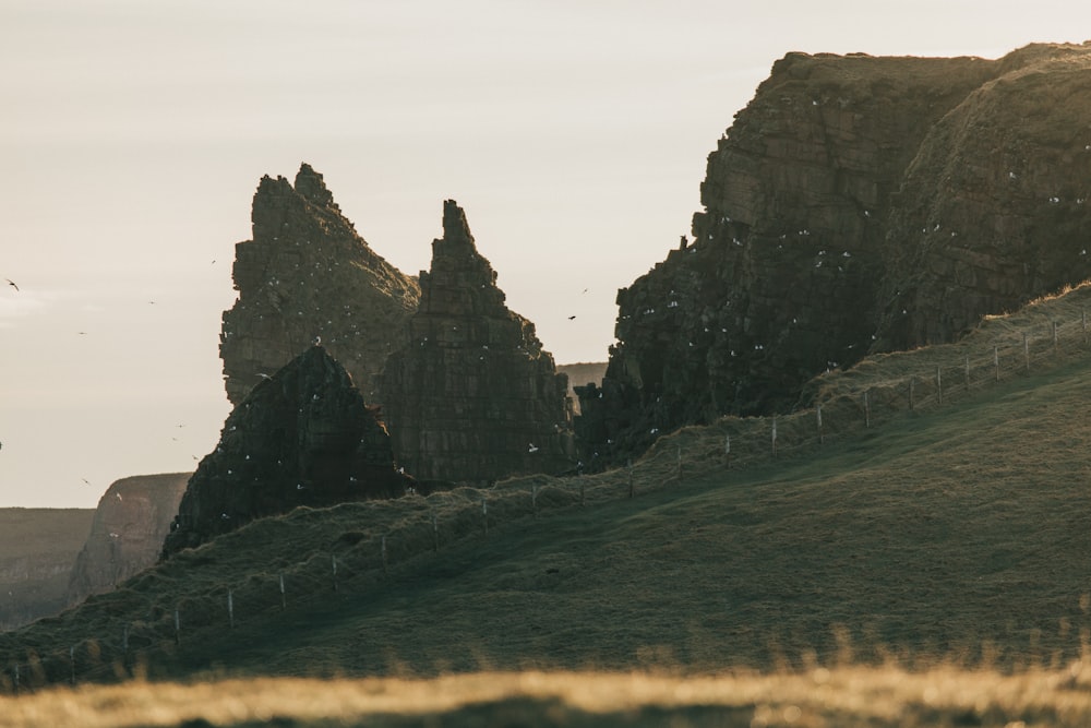 green grass field near brown rock formation during daytime