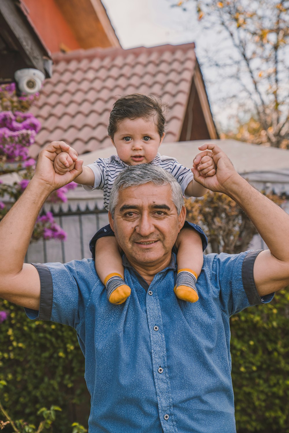 man in blue button up shirt holding boy in white and black stripe shirt