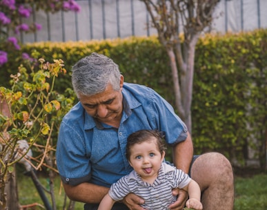 man in blue button up shirt carrying baby in black and white stripe shirt