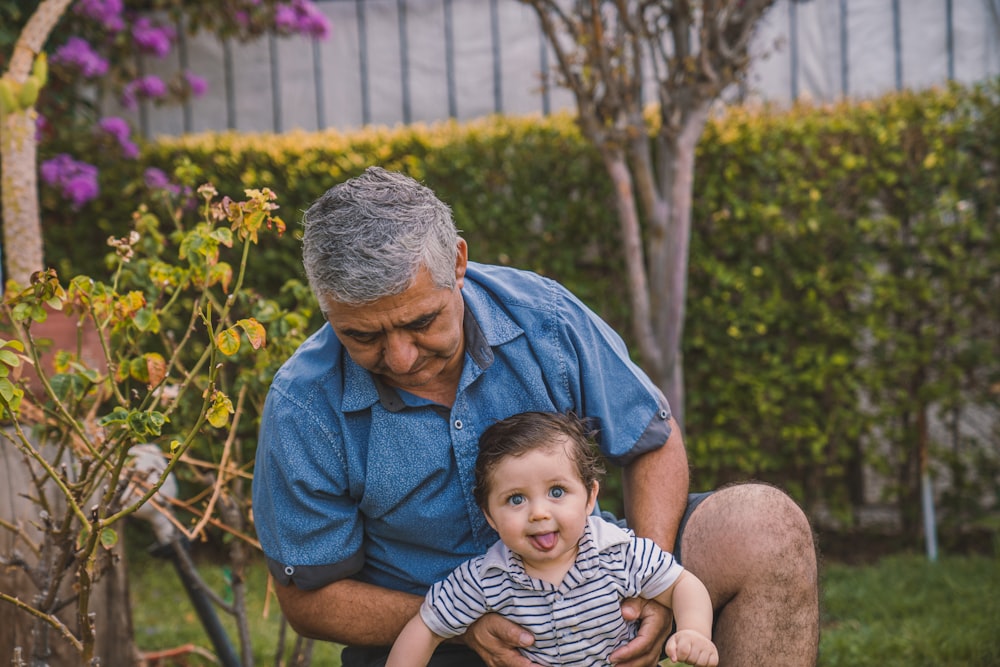 man in blue button up shirt carrying baby in black and white stripe shirt