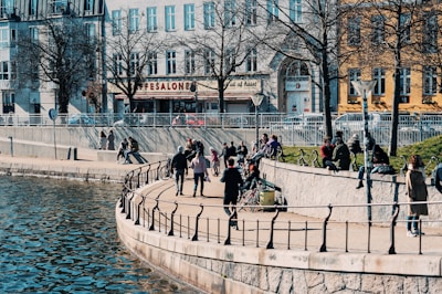 A scenic riverside promenade lined with trees and people enjoying a sunny day.