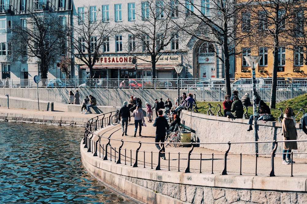 people walking on sidewalk near body of water during daytime