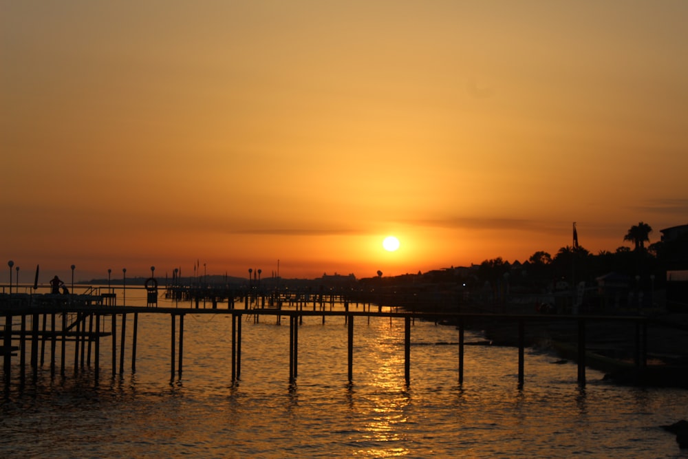 silhouette of people on dock during sunset