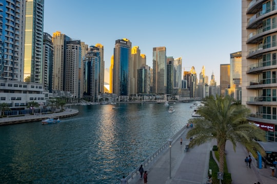 people walking on sidewalk near body of water during daytime in Dubai Marina Walk - Emaar United Arab Emirates