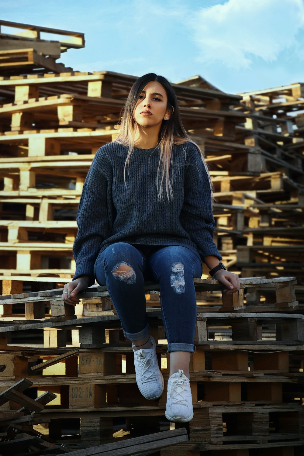 woman in gray sweater and blue denim jeans sitting on brown wooden chair