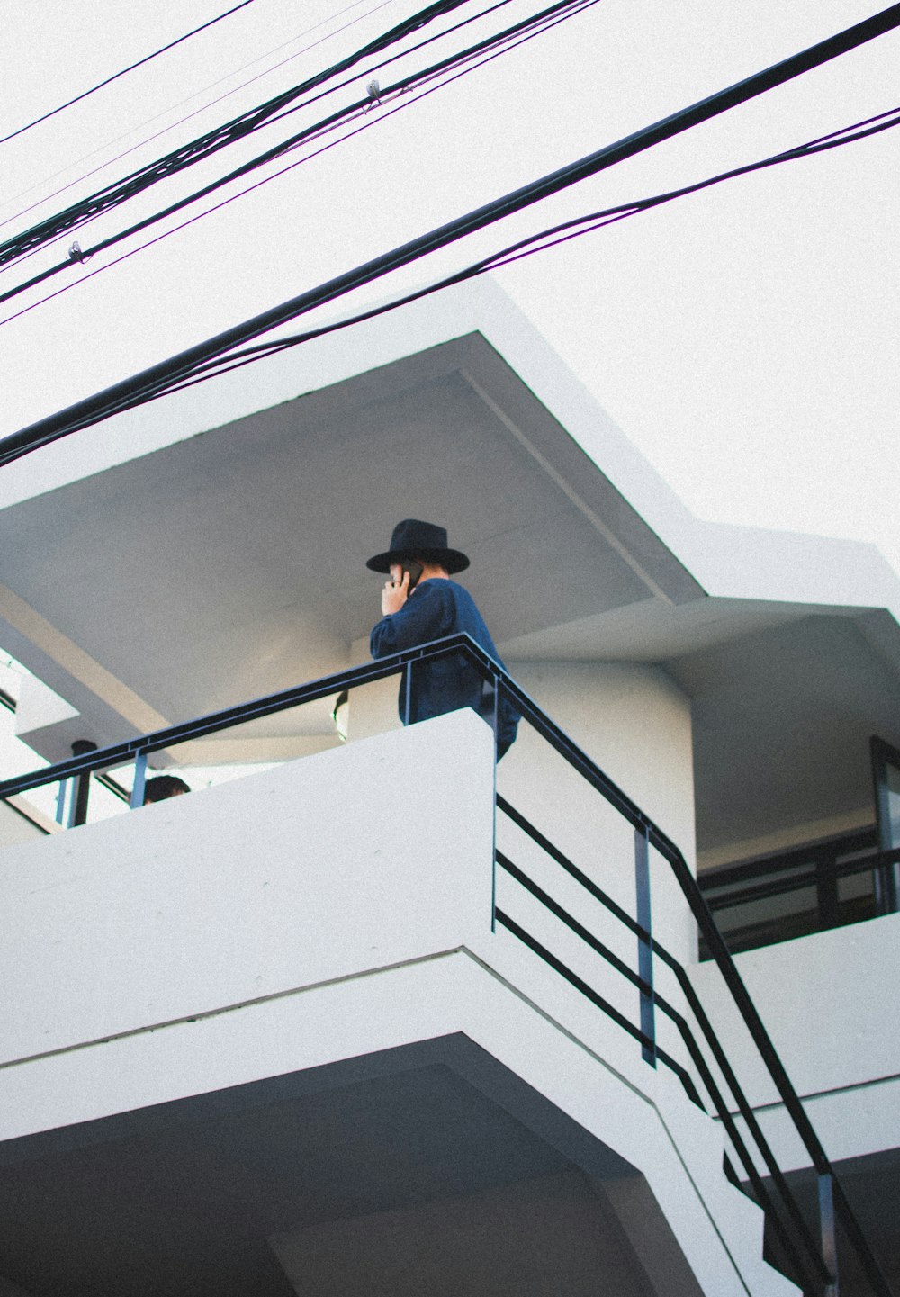 man in black hat and blue long sleeve shirt standing on white staircase