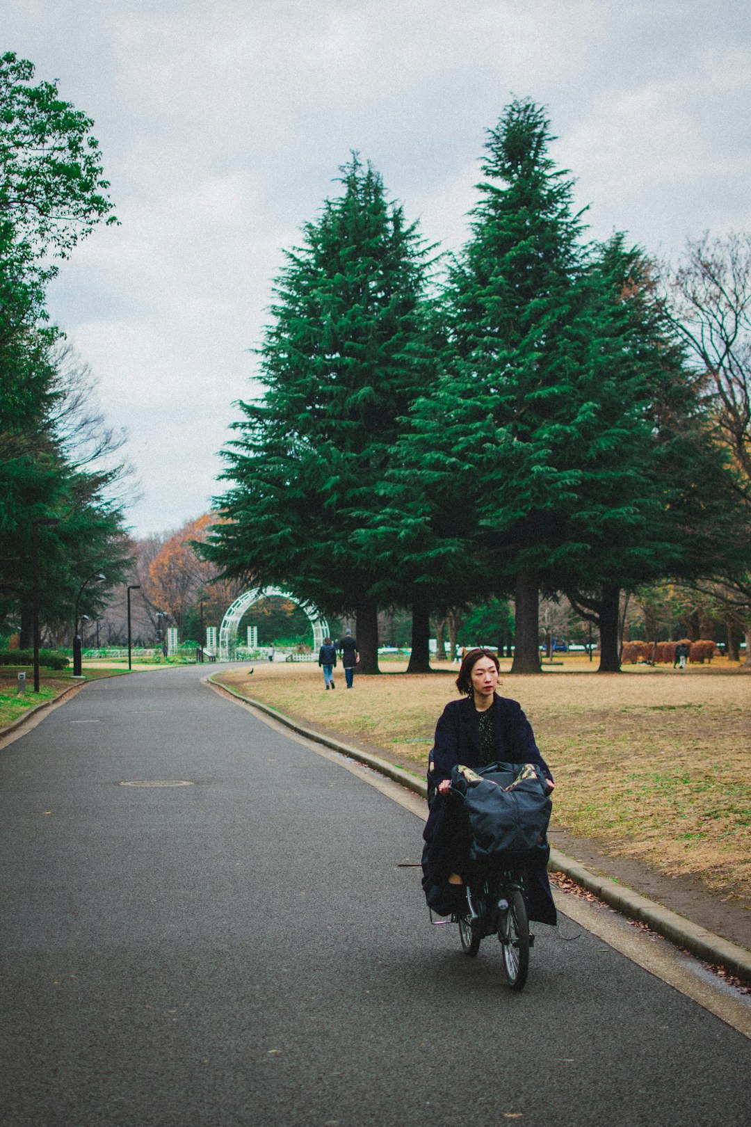woman in black jacket and black pants sitting on black stroller on gray concrete road during