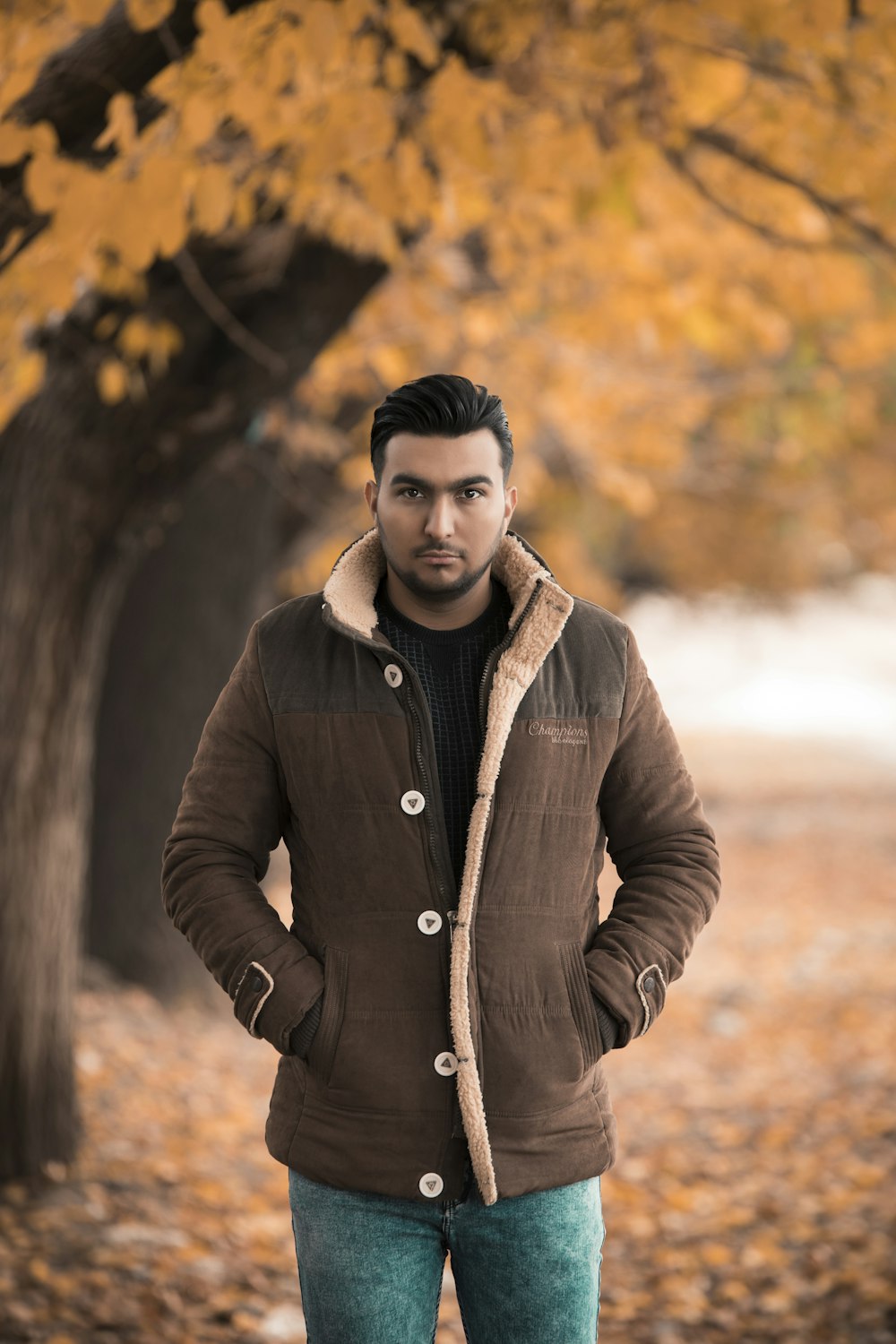man in brown button up jacket standing near brown trees during daytime