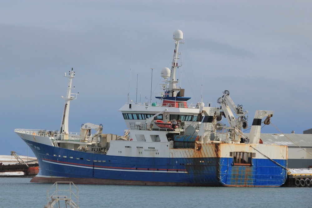 navio branco e azul no cais durante o dia