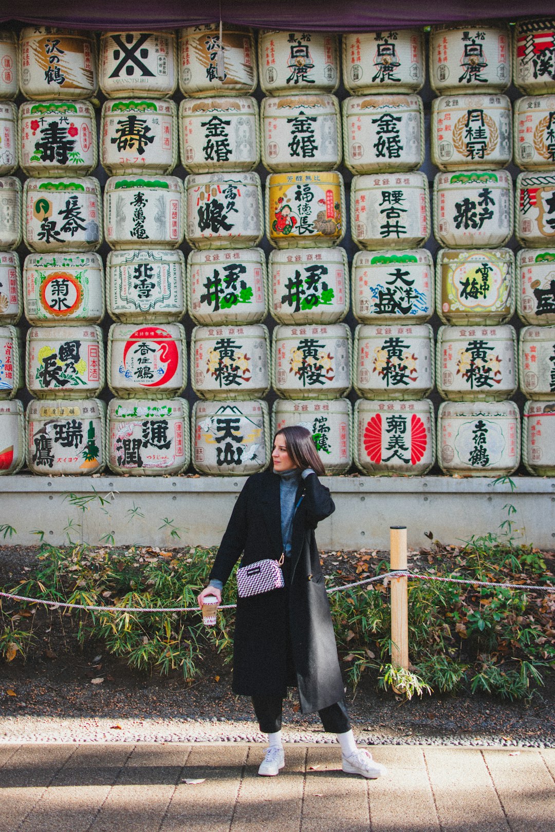 woman in black long sleeve shirt standing in front of white wall with kanji text