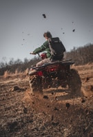 man riding red atv on brown field during daytime