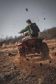 man riding red atv on brown field during daytime