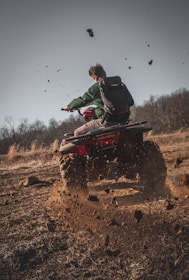 man riding red atv on brown field during daytime