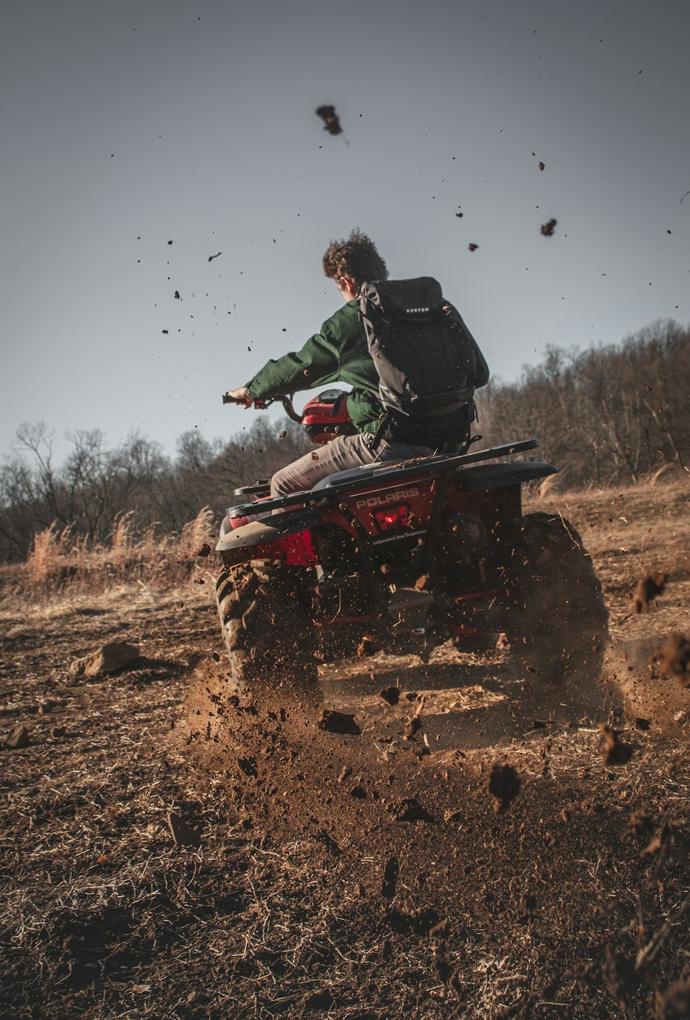man riding red atv on brown field during daytime