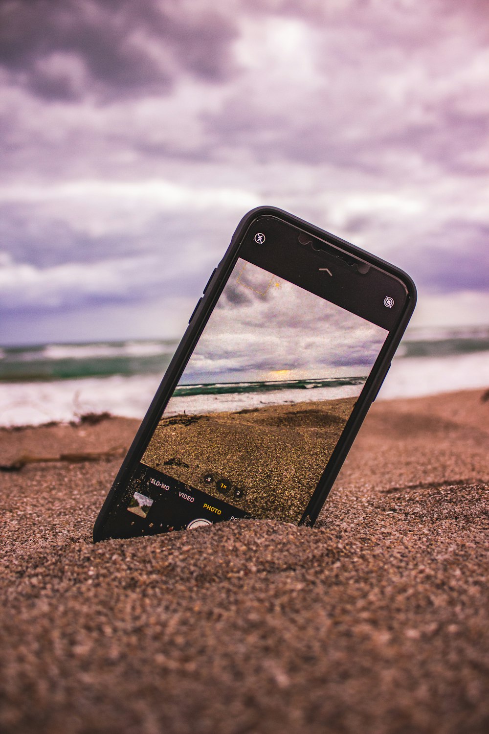 black and white iphone case on brown sand near body of water during daytime