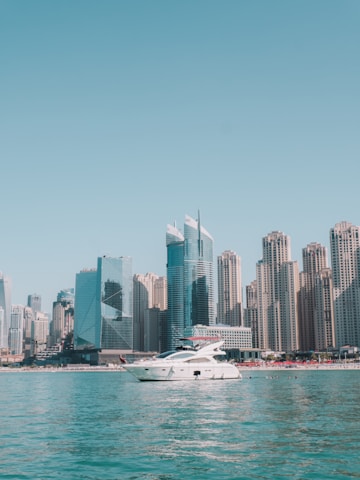 A stylish yacht cutting through Miami’s turquoise waters under a bright blue sky, with a modern city skyline in the background.