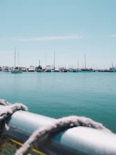 A serene marina under a clear blue sky with yachts docked at the port.