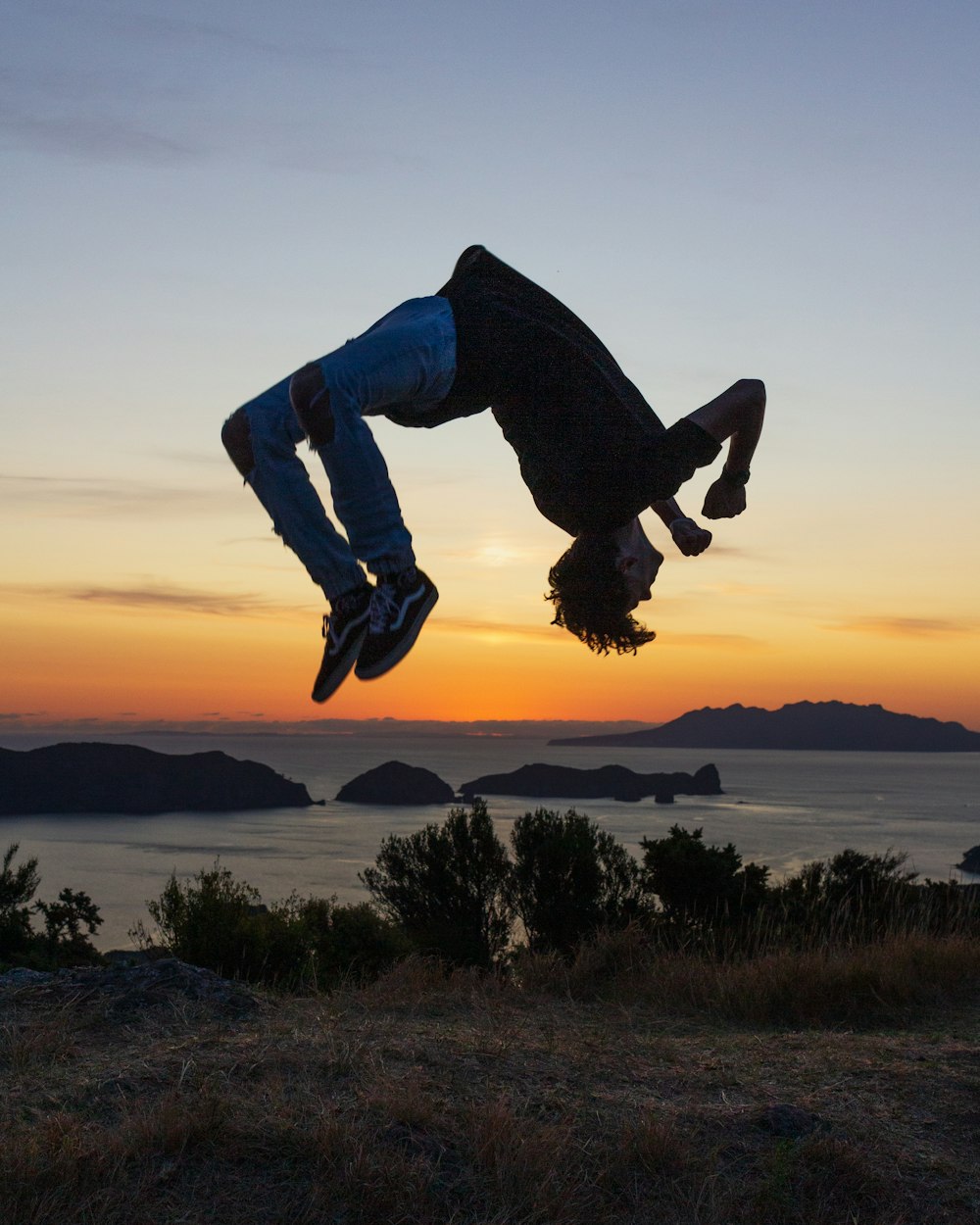 man in blue denim jeans jumping on brown field during sunset