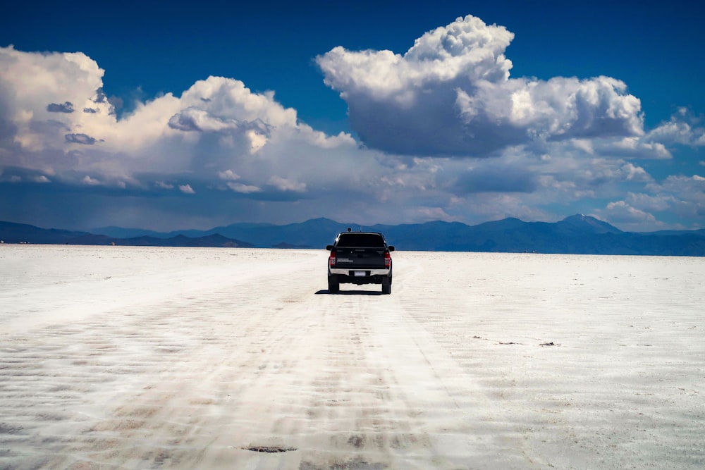 black suv on white sand under white clouds and blue sky during daytime