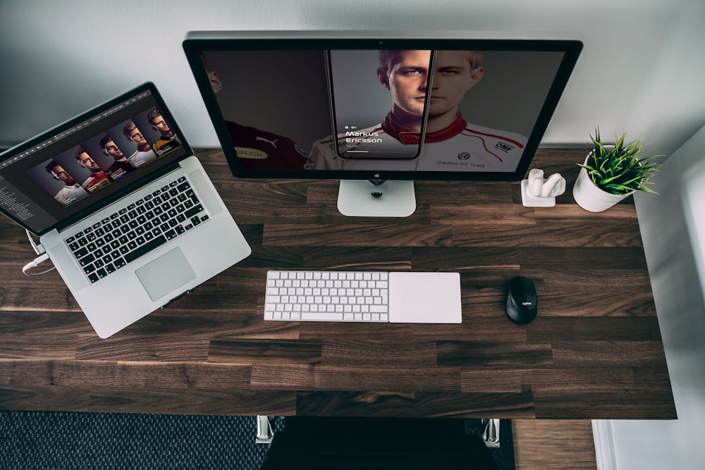 silver imac beside black corded computer mouse and white apple keyboard on brown wooden desk