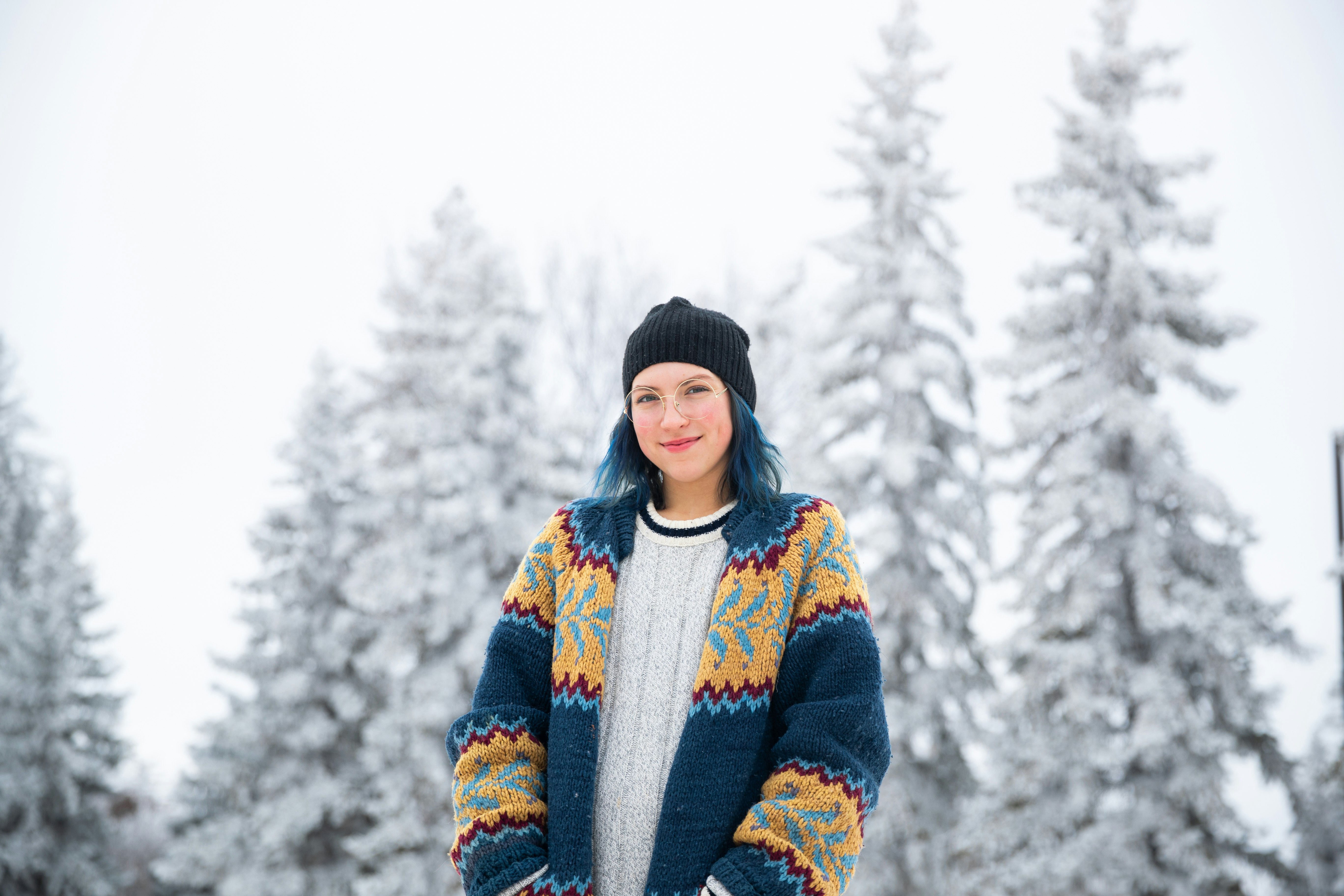 woman in blue and white sweater standing on snow covered ground during daytime