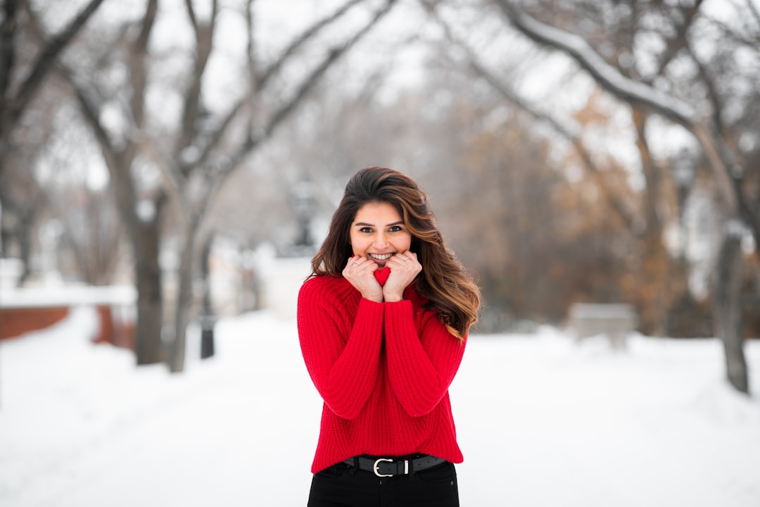 woman in red sweater standing on snow covered ground during daytime