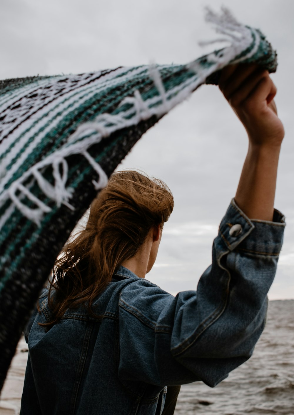 woman in blue denim jacket holding black smartphone