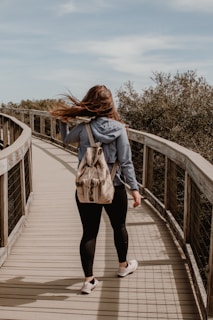 woman in brown coat walking on wooden bridge during daytime