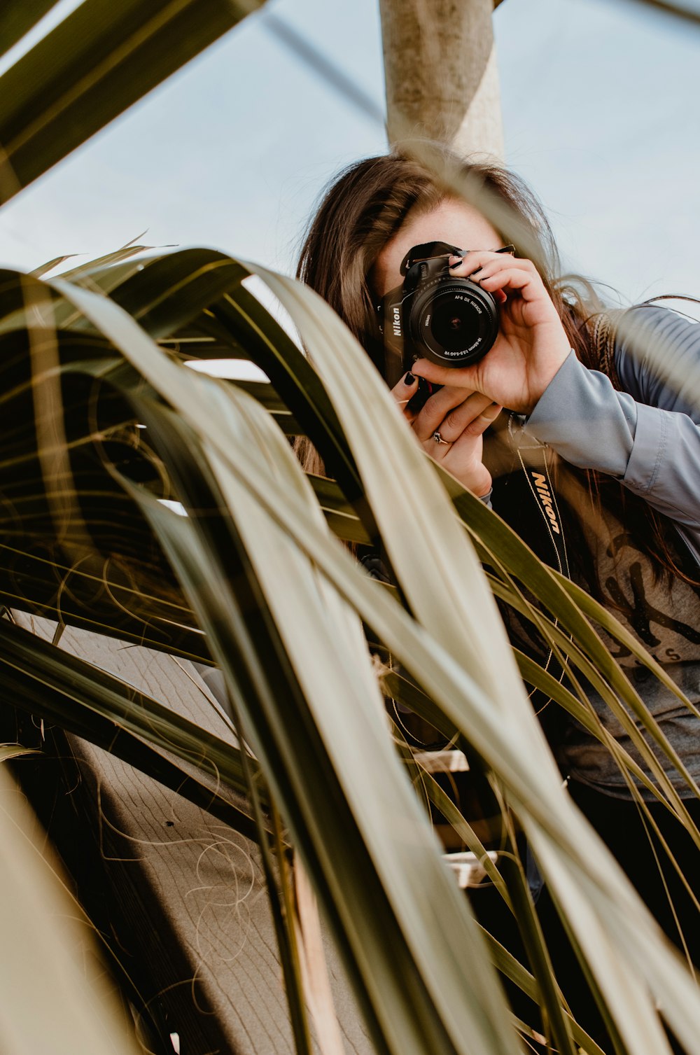 person in gray jacket holding black dslr camera