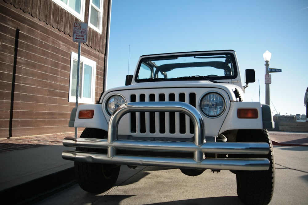 white and blue jeep wrangler parked near white building during daytime