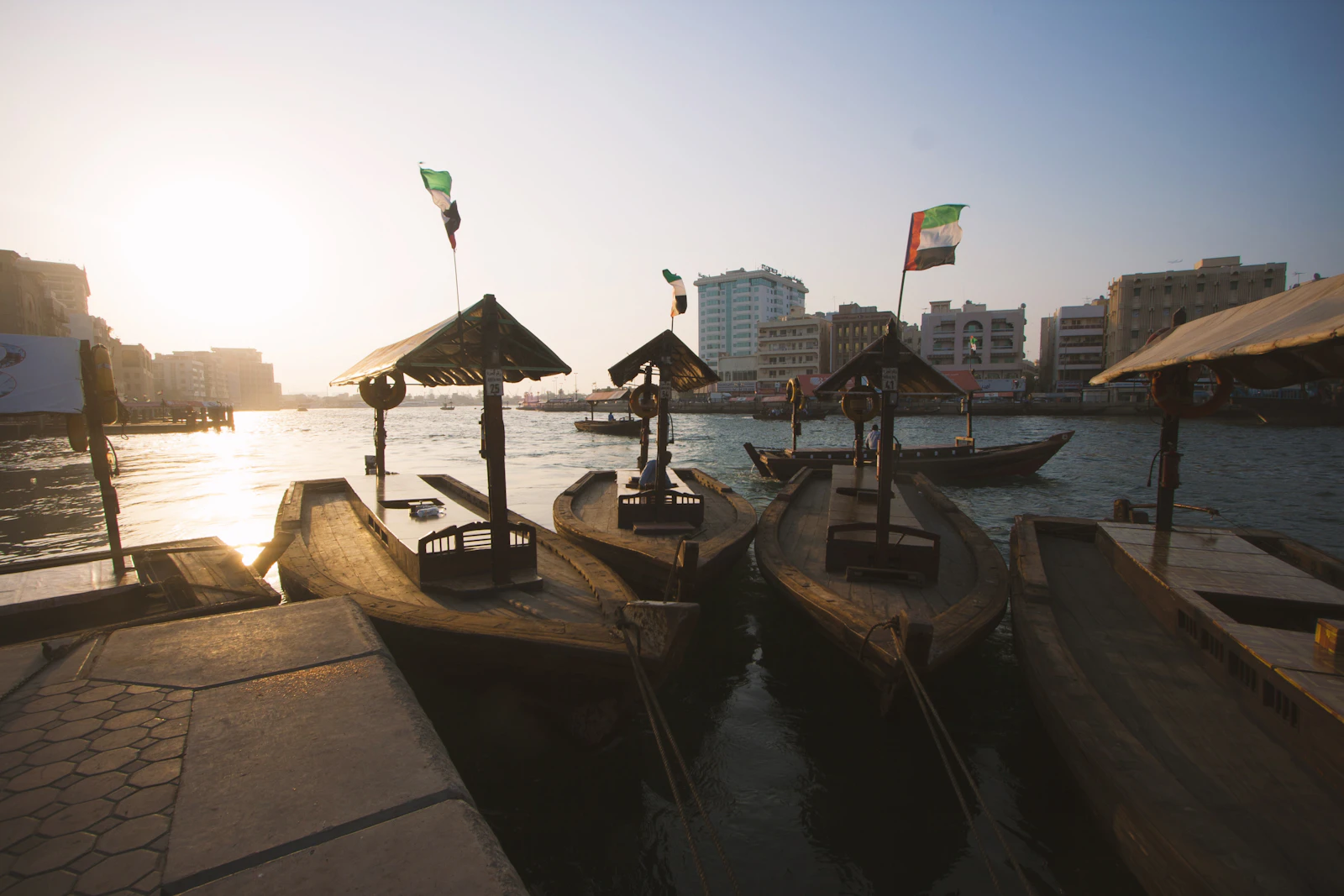 Travel photograph: Wooden abras wait at the edge of Dubai Creek in warm low sunlight.