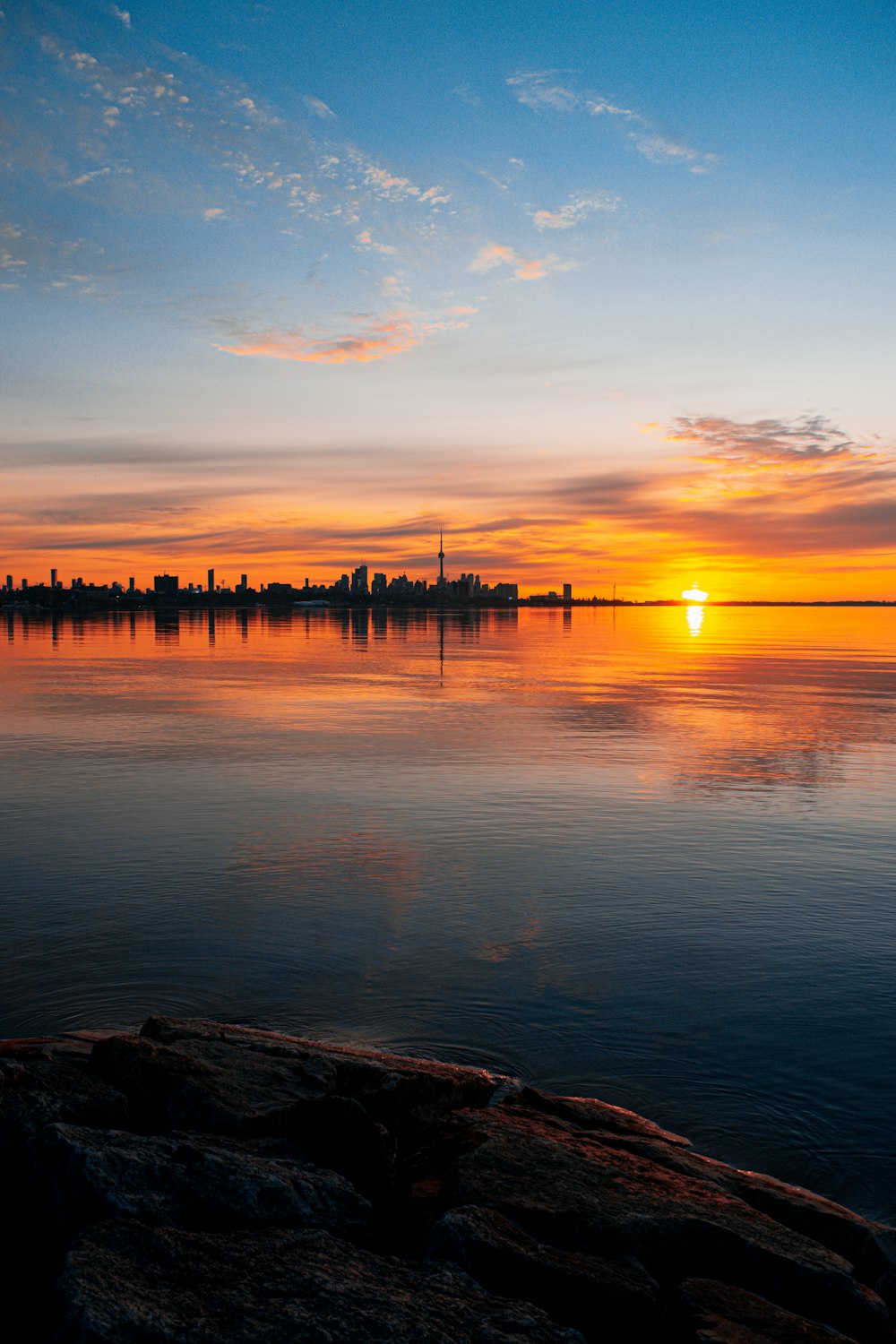 silhouette of dock on body of water during sunset