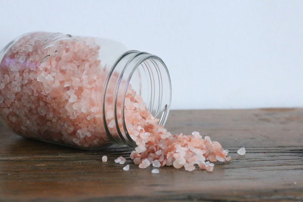 Glass jar spilling pink Himalayan bath salt