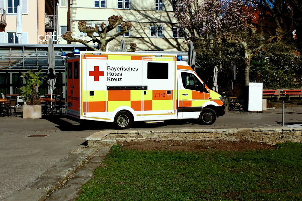 white and red ambulance truck parked near brown building during daytime