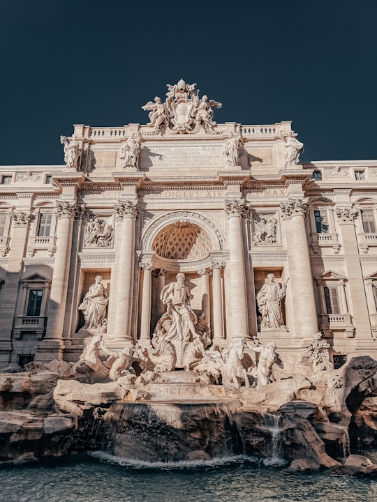 white concrete building under blue sky during daytime in Trevi Fountain Italy