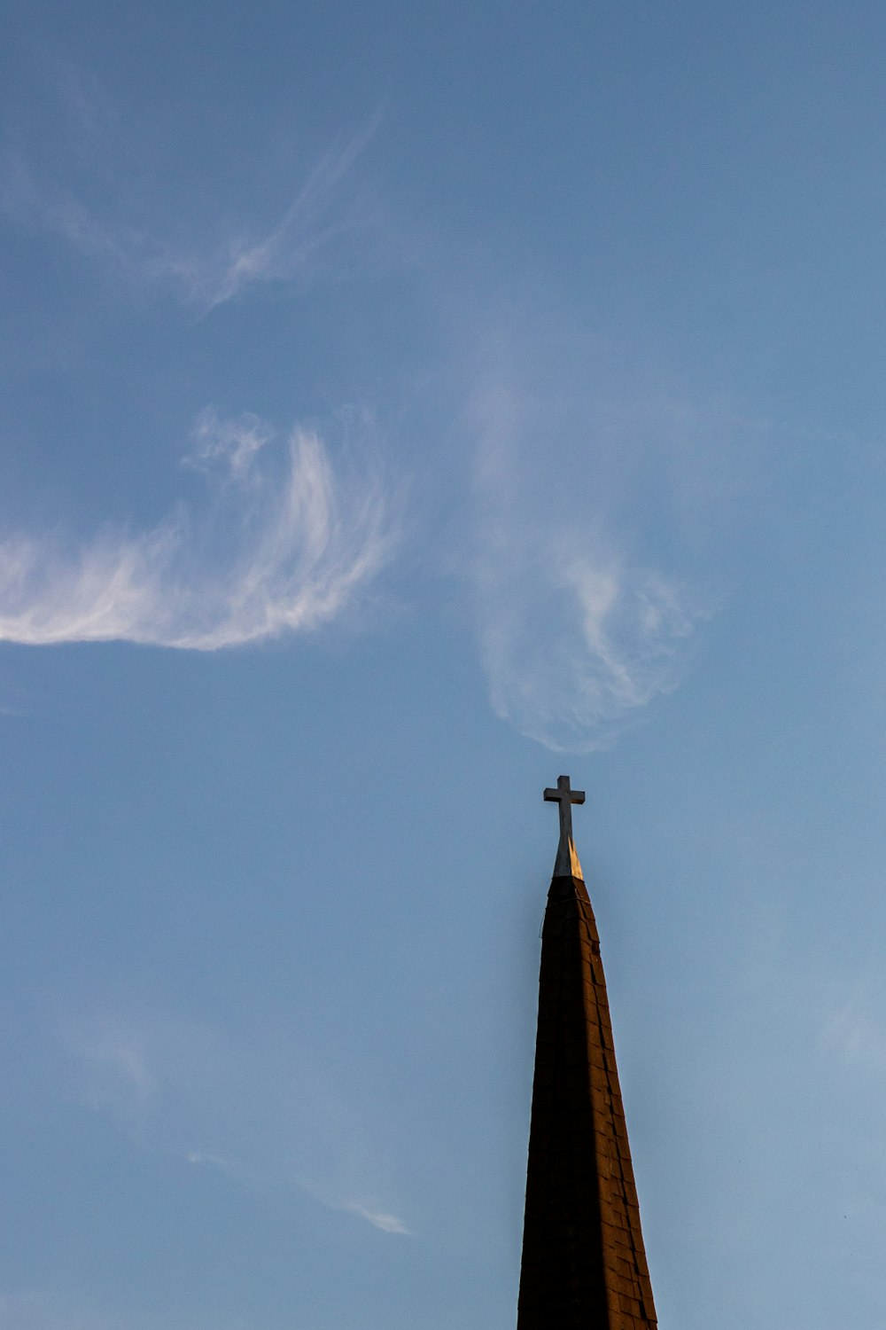 black cross under white clouds and blue sky during daytime