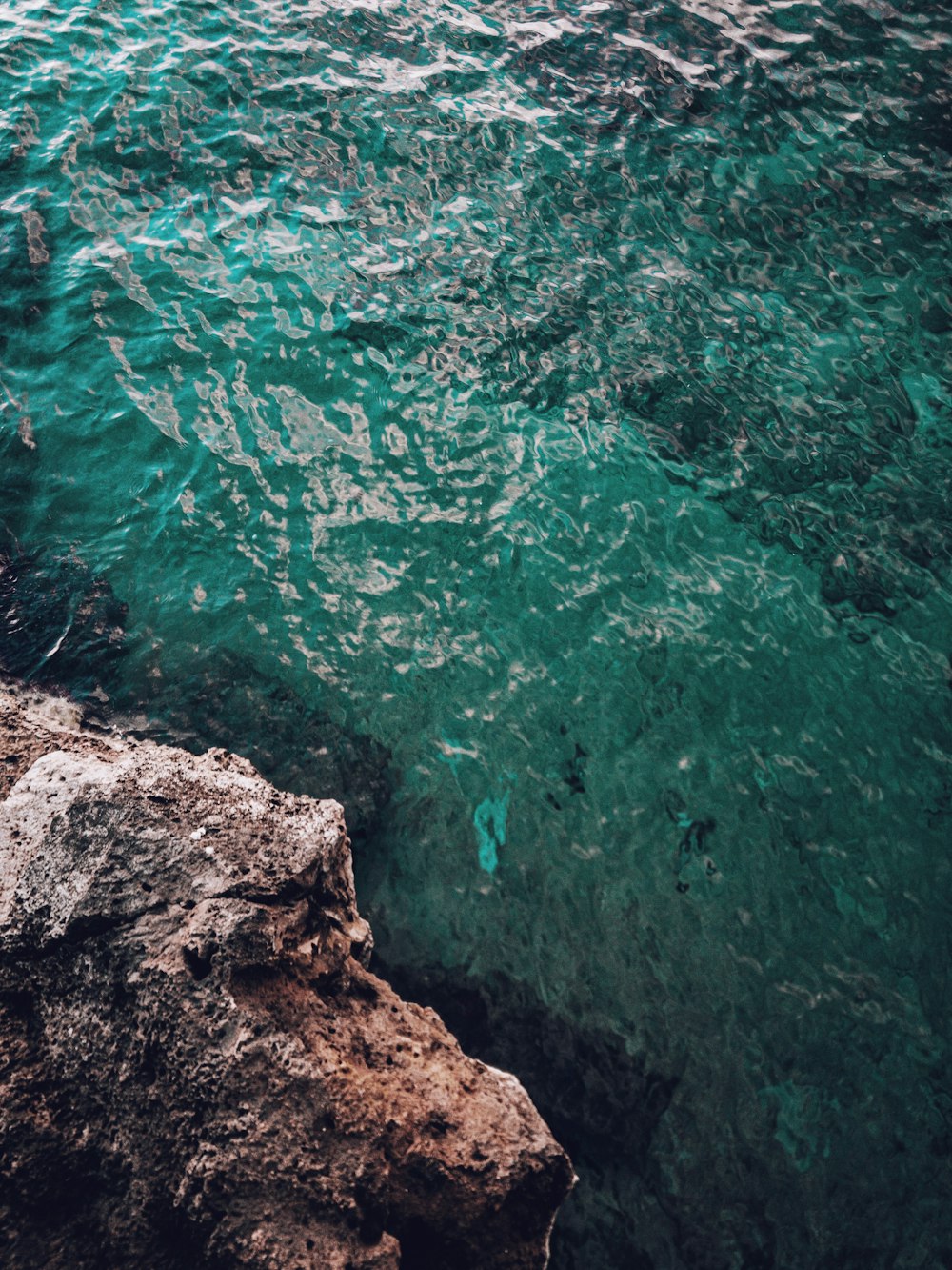 brown rocky mountain beside body of water during daytime