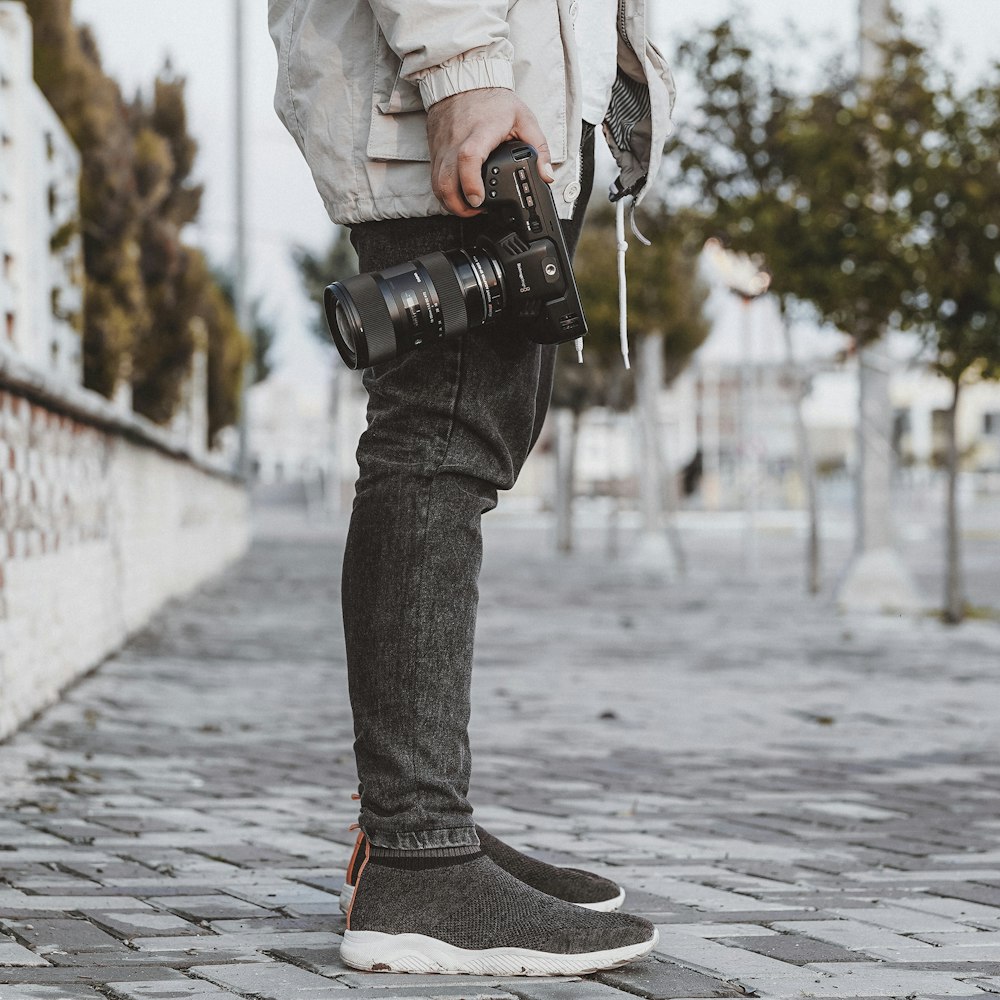 person in black denim jeans and black and red nike sneakers walking on sidewalk during daytime